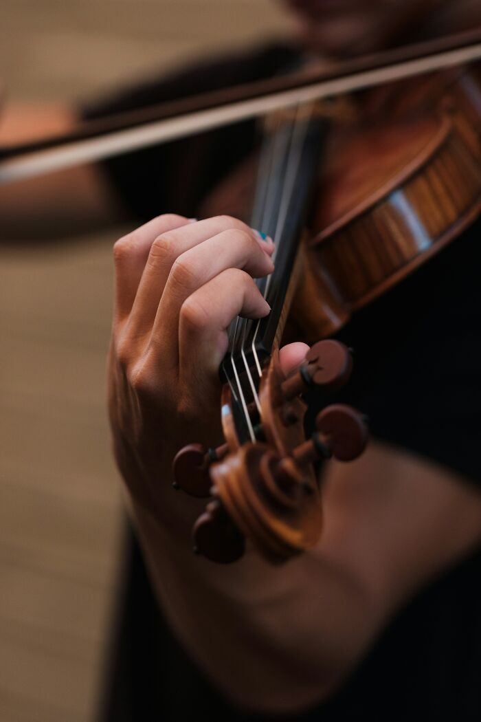 "Close-up of hands playing a violin, representing movie moments that defy logic."