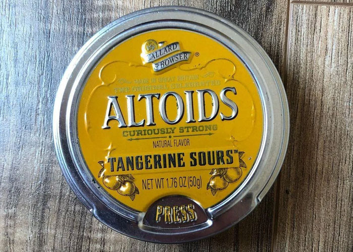Altoids Tangerine Sours tin, a product that failed despite being good, on a wooden surface.