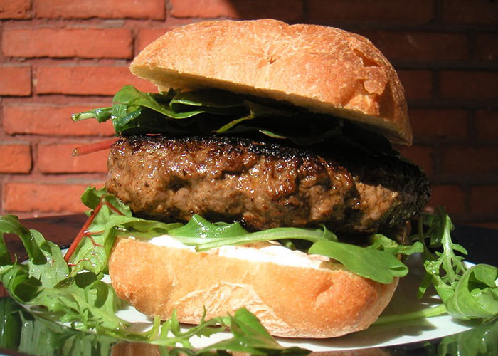A gourmet burger with fresh greens placed on a rustic bun, illustrating a product that failed despite being good.