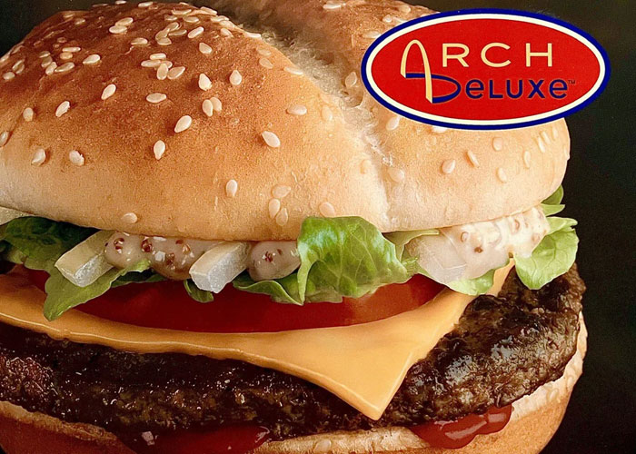 Arch Deluxe burger, a product that failed despite being good, featuring lettuce, cheese, and sauce in a sesame seed bun.