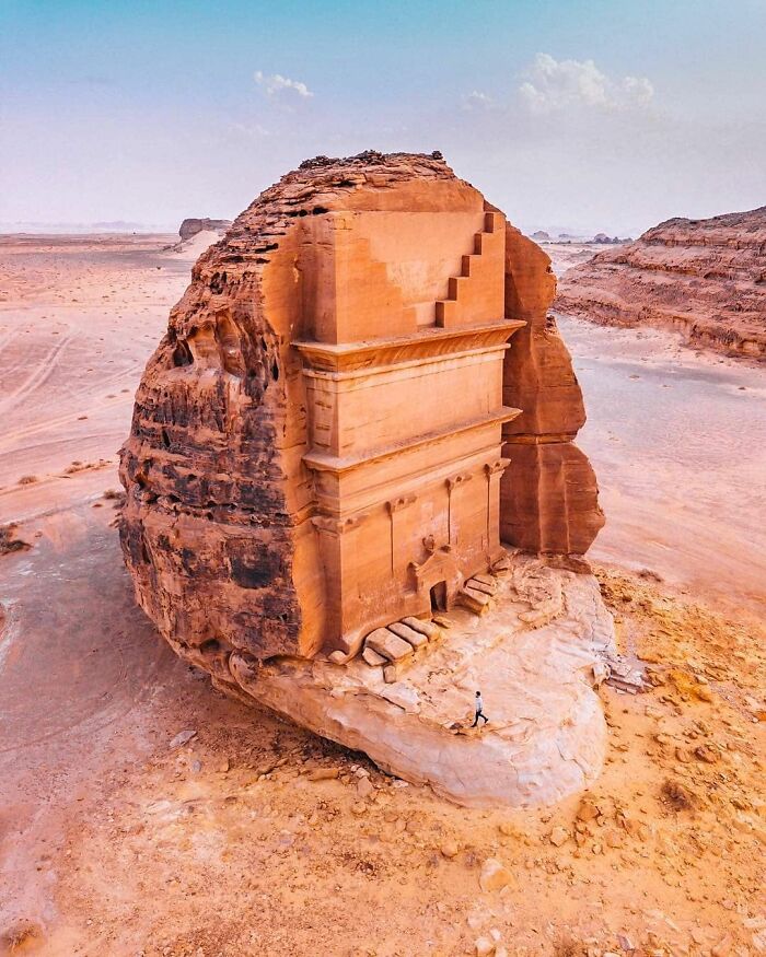 Ancient artefact, a carved sandstone tomb in a desert landscape, illustrating remarkable historical preservation.