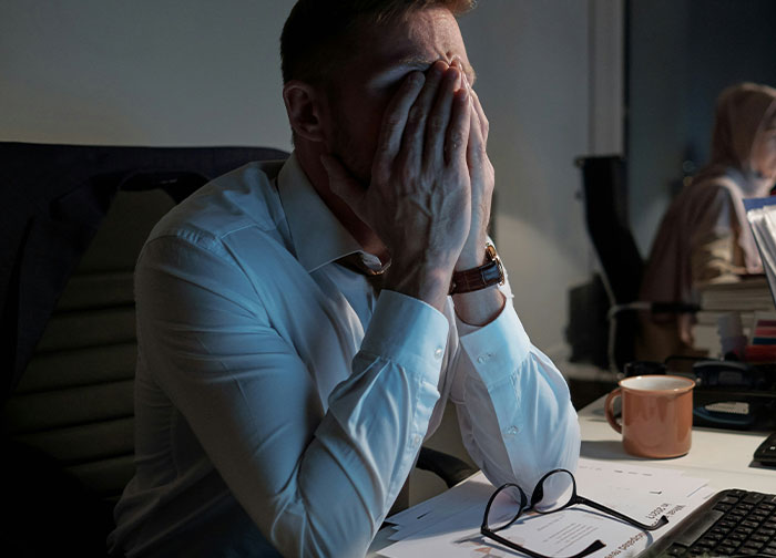 Frustrated man in office with hands on face, representing quitting a job abruptly.