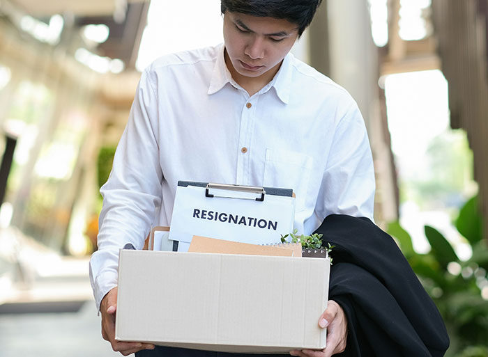 Man holding box with resignation letter, symbolizing quitting job on the spot.