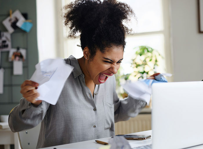 Person expressing frustration, tearing papers at a desk, highlighting the moment of quitting a job on the spot.