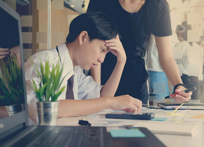 A stressed employee in an office environment, contemplating quitting their job amid paperwork and discussions.