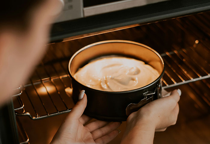 Person placing cake batter in the oven, illustrating a moment before quitting their job spontaneously.
