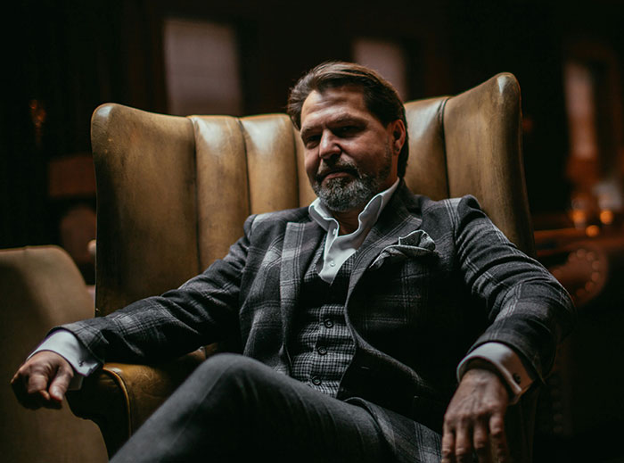 Man in a plaid suit sitting in a dimly lit room, representing the concept of quitting a job on the spot.