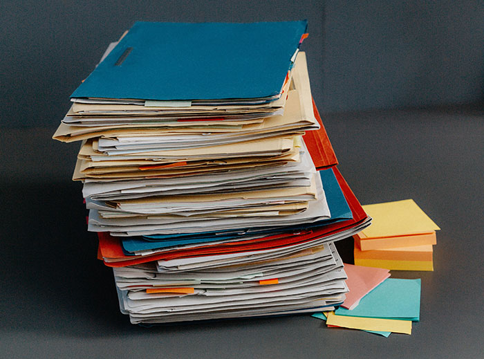 Stack of colorful folders and papers on a desk, representing a busy work environment before quitting a job.