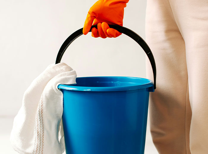 Person wearing gloves holding a blue bucket and white cloth, symbolizing quitting a job on the spot.