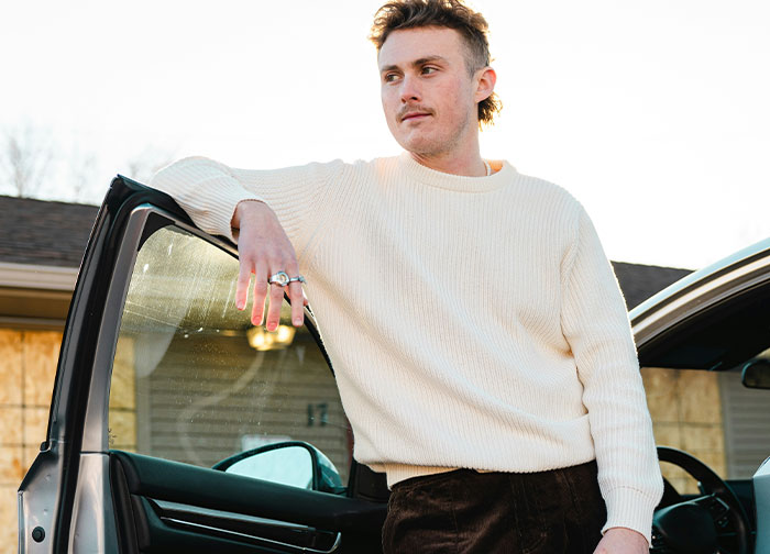 Person leaning on car door, wearing a cream sweater, representing people who quit their job on the spot.