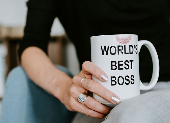 Person holding a mug with the text "World's Best Boss," featuring a lipstick mark, illustrating job resignation stories.