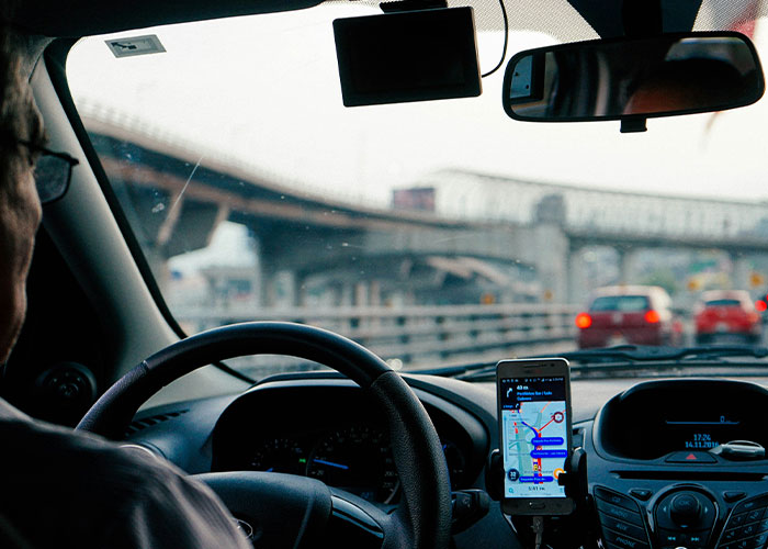 Driver in a car views GPS on a smartphone, depicting career change or job quitting scenario.