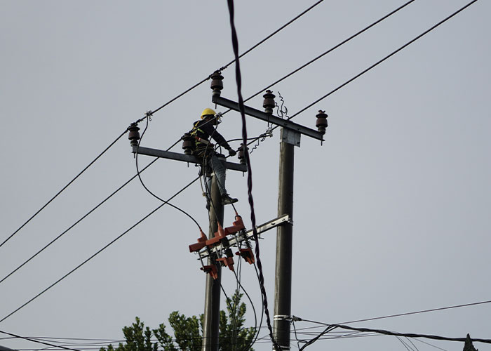 Worker on a utility pole adjusting cables, related to people quitting their jobs abruptly.