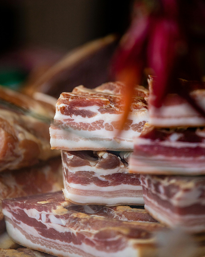Slices of bacon stacked in a display, highlighting marbled fat and meat texture.