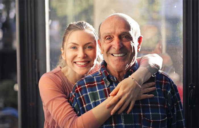 Smiling young woman embracing happy older man, capturing a proud moment with family and warmth indoors.
