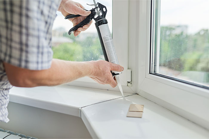 Person applying caulk to a window frame, highlighting common DIY mistakes people make.