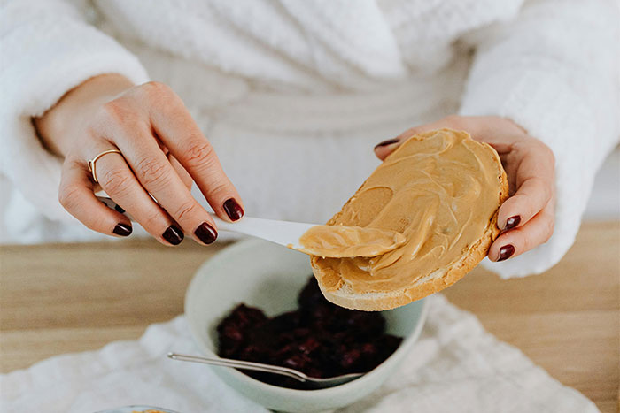 Person spreading peanut butter on bread, illustrating a moment of doing something the wrong way at home.