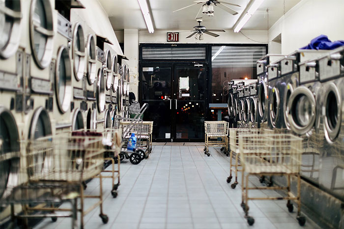 Rows of washing machines and laundry carts in a laundromat, illustrating moments of people doing things the wrong way.