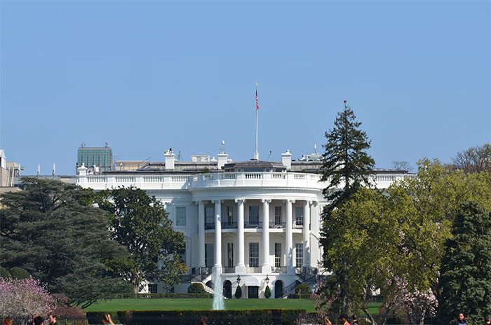 The White House surrounded by trees on a clear day.