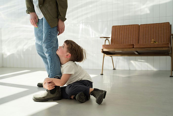 Young child hugging adult's leg, showing a moment of realization and doing something the wrong way in a bright room.