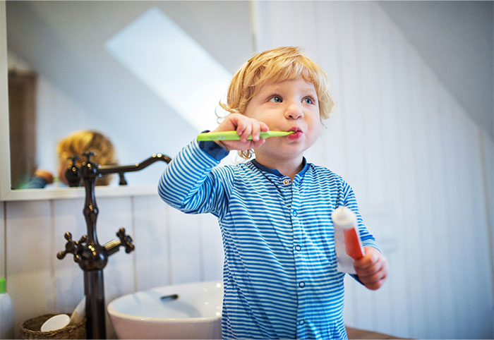 Young child in striped pajamas brushing teeth in bathroom illustrating moments of doing something the wrong way