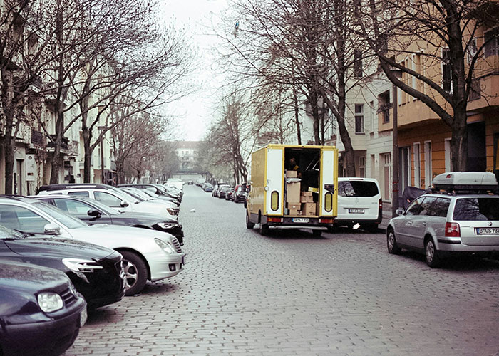 Yellow moving truck parked in cobblestone street surrounded by cars and autumn trees, related to realtor parking issue.