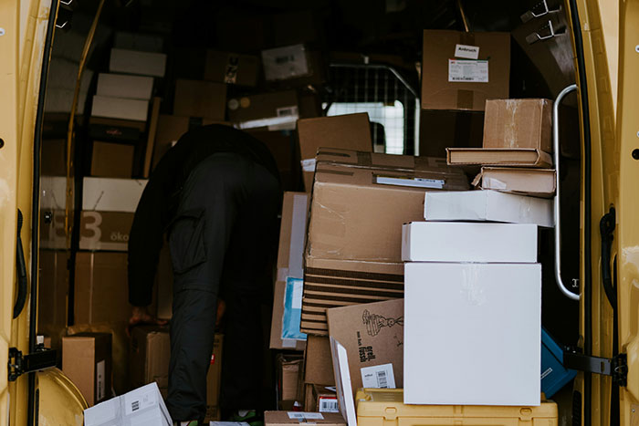 A delivery van filled with packages, a person organizing boxes, representing challenges faced on a first workday.