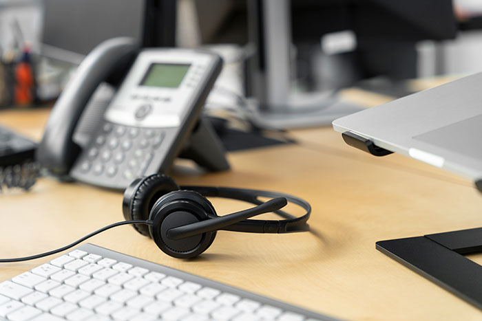 Keyboard, headset, and office phone on a desk representing the first day quitting job experience.