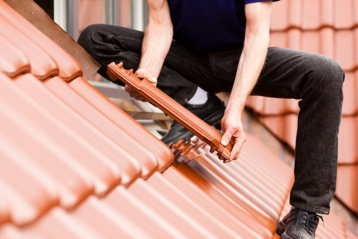 Person installing roof tiles, which can be a demanding job, representing reasons people quit jobs on the first day.