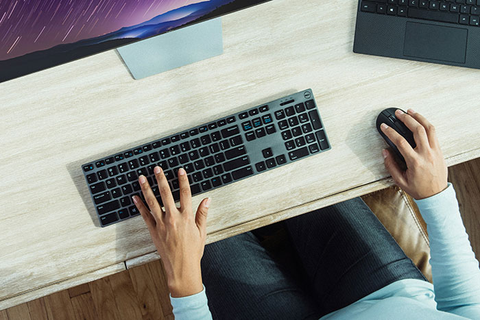 Person at desk using computer keyboard and mouse, possibly experiencing frustration related to quitting a job on the first day.