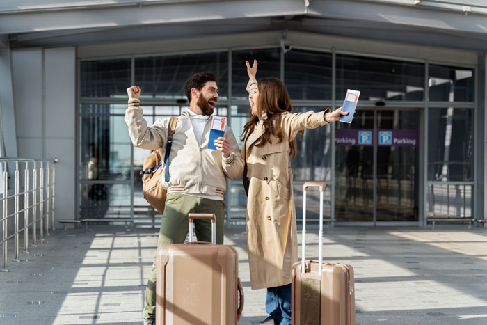 A couple at the airport with luggage and boarding passes, excited for their travel adventure.