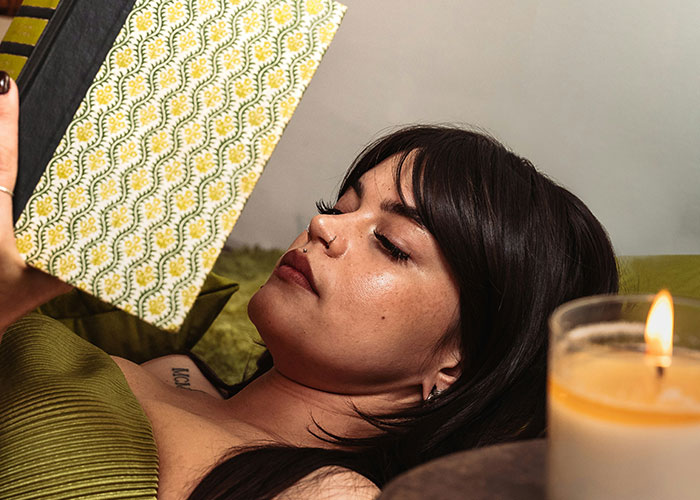 Woman relaxing and reading a book by candlelight, dealing with ex’s affair child issues. Woman relaxing and reading a book by candlelight, dealing with ex’s affair child issues.