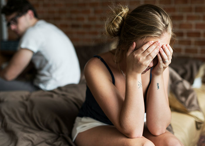 Woman looking distressed with head in hands; relationship conflict and smear campaign theme. Woman looking distressed with head in hands; relationship conflict and smear campaign theme.