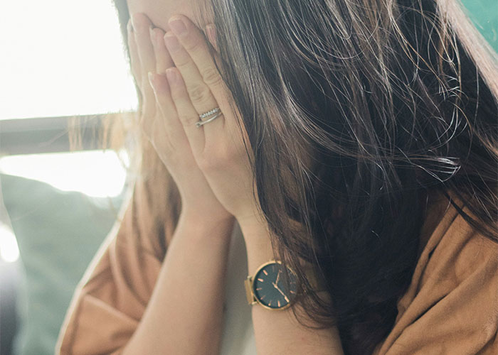 Woman covering her face with hands, showing emotional distress, wearing a watch and ring, related to affair child issue. Woman covering her face with hands, showing emotional distress, wearing a watch and ring, related to affair child issue.