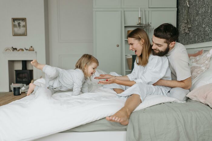 Happy couple with child on bed, capturing family moments, focusing on the dynamics of marriage and spouse relationships.