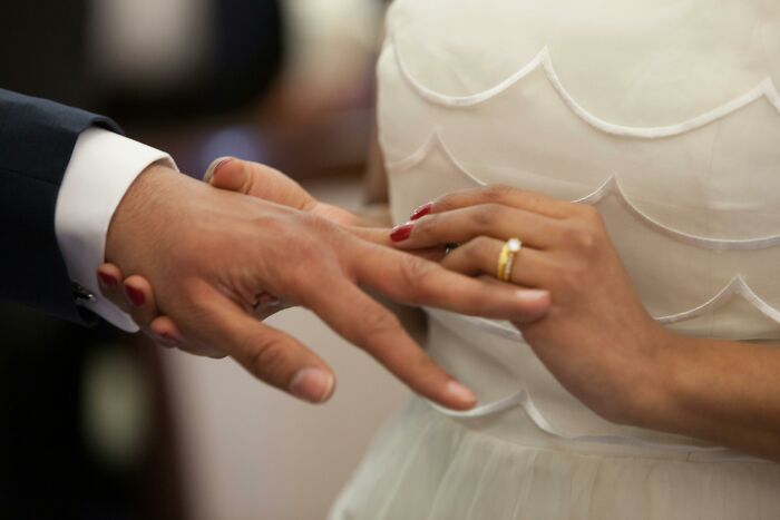 Hands exchanging rings, symbolizing marriage commitment, possibly evoking regret in spouse relationships.