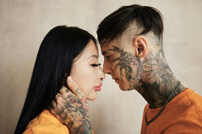 A couple with tattoos is in an intimate pose, reflecting on marriage and spouse dynamics.