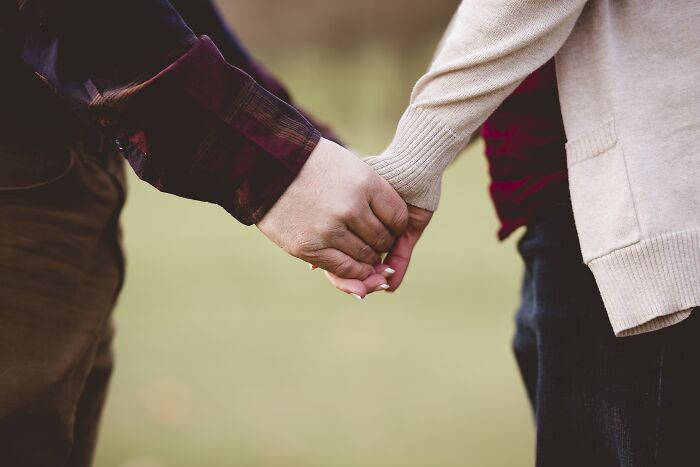 Two people holding hands, symbolizing marriage-spouse connection in a serene outdoor setting.