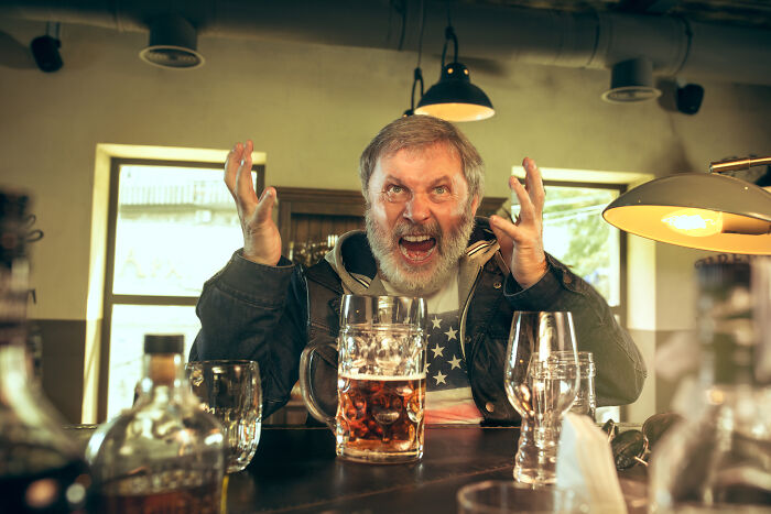 Man expressing frustration at a bar, surrounded by drinks, illustrating challenges in respect and relationships.