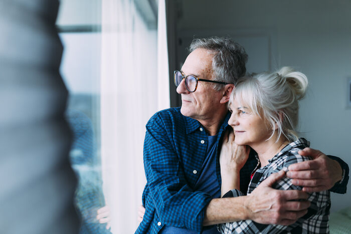 Senior couple embracing by a window, symbolizing respect and enduring relationships.