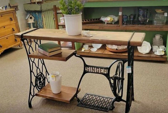 Repurposed sewing machine table with wooden shelves inspires recycling in home decor.