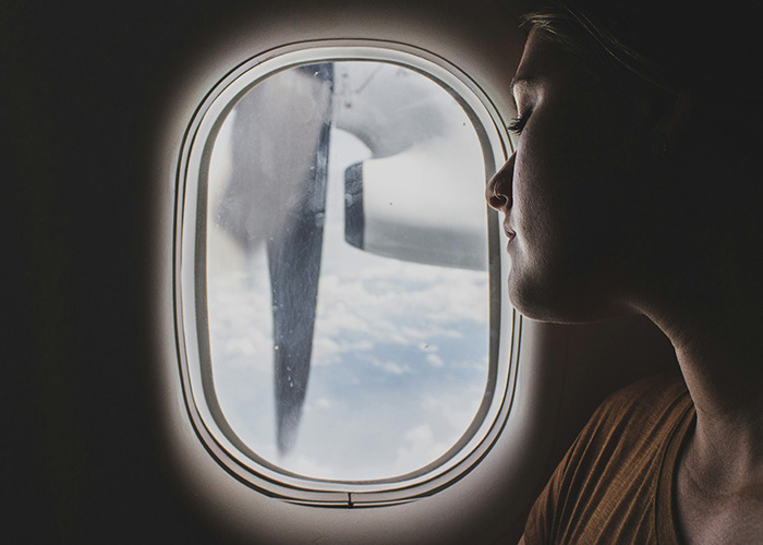 Woman gazing out airplane window, contemplating proactive health measures for RFK Jr.'s role as Health Secretary.