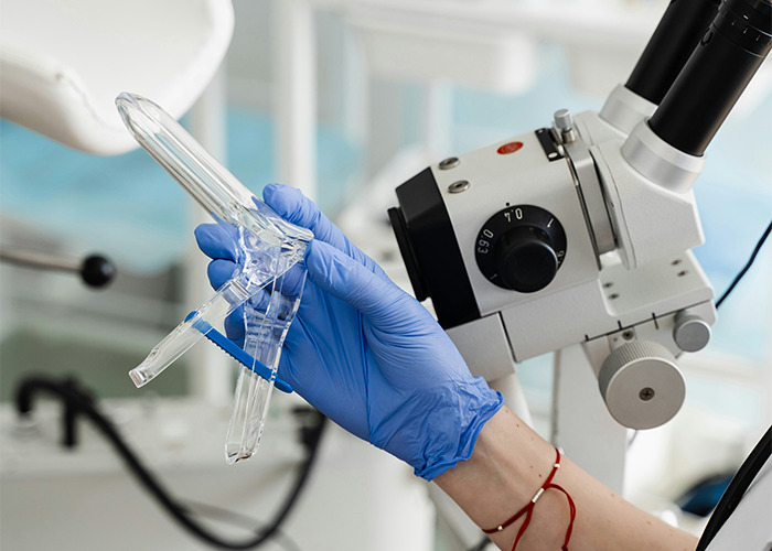 A gloved hand holding a medical instrument near a microscope, focusing on health secretary readiness.