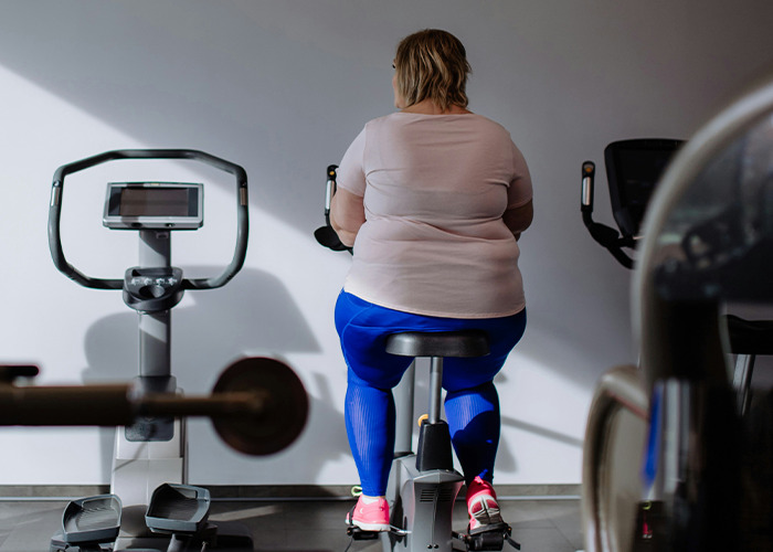 Woman on exercise bike, focusing on proactive health measures in a gym setting.