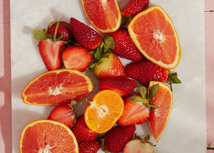 Sliced citrus fruits and strawberries on a marble surface, symbolizing proactive health measures.