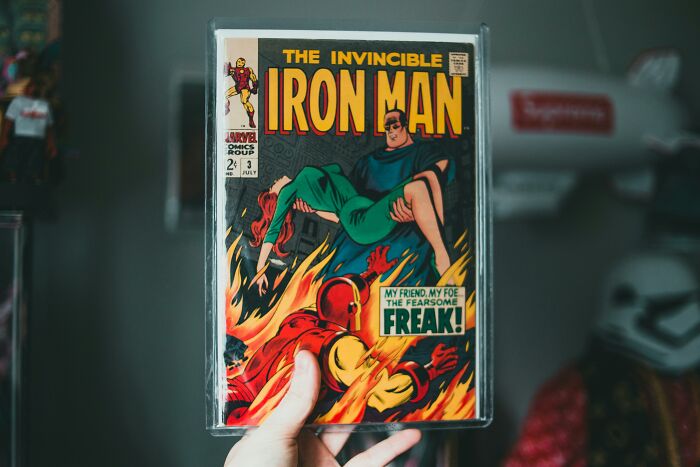 Hand holding vintage Iron Man comic; symbol of rich people's annoying collectibles.