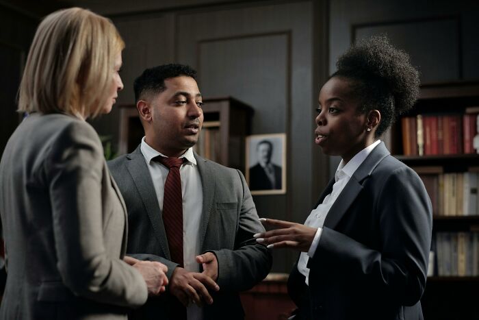 Three people in a serious discussion in an office, illustrating a concept linked to rich people as potentially annoying.