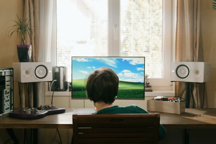 Person at a computer desk with a view of nature outside, reflecting on stories of overnight wealth.