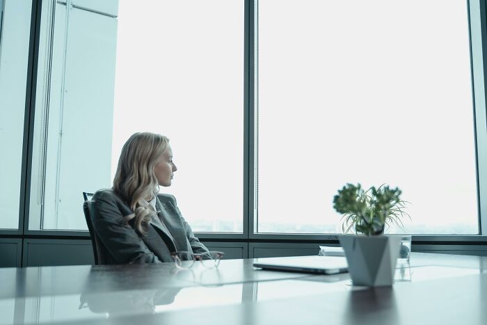 Businesswoman gazing out of an office window, representing stories of overnight wealth.
