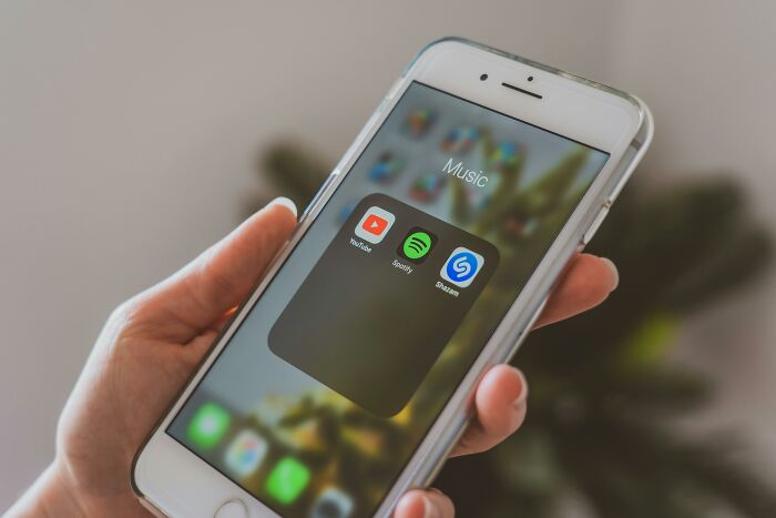 Phone displaying music apps, reflecting stories of overnight wealth and Bitcoin billionaires.